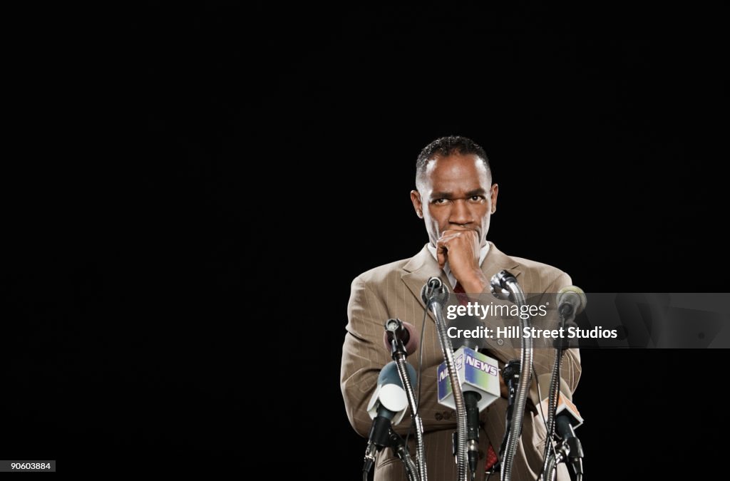 African man looking pensive at podium with microphones