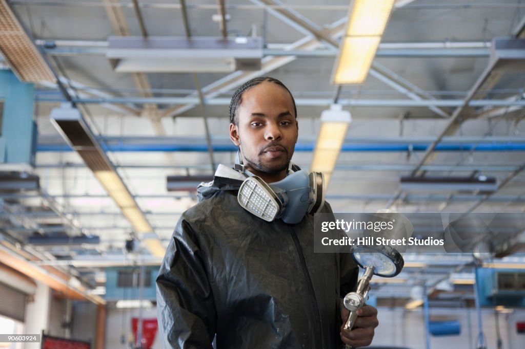 Mixed race man holding equipment in auto body shop