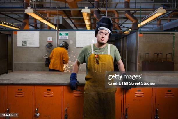 mixed race welder leaning against lockers - reconversão profissional imagens e fotografias de stock