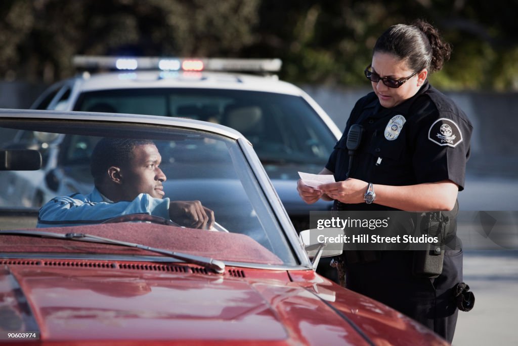 Policewoman checking paperwork of man in convertible