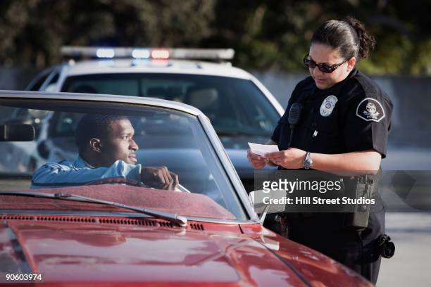 policewoman checking paperwork of man in convertible - cop 21 imagens e fotografias de stock