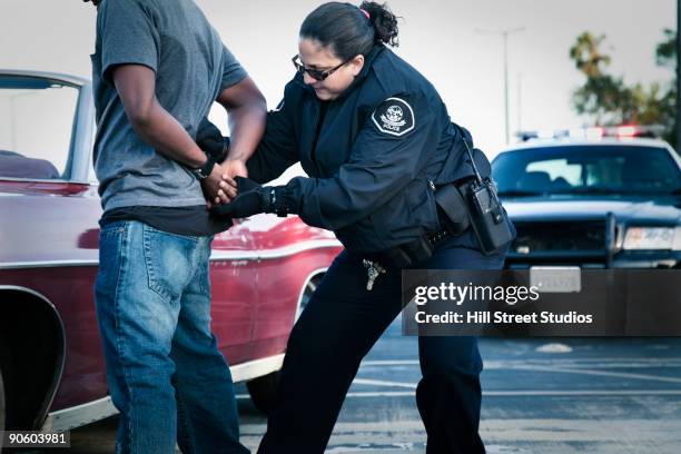 hispanic policewoman handcuffing man - arresto foto e immagini stock