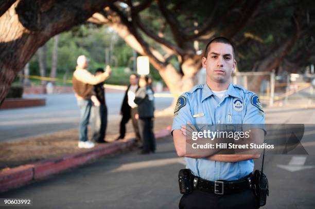 serious policeman standing with arms crossed - hill street studios stock-fotos und bilder