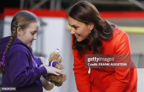 Britain's Catherine, Duchess of Cambridge is given two teddy bears by patient Eva during her visit to officially open the Mittal Children's Medical...