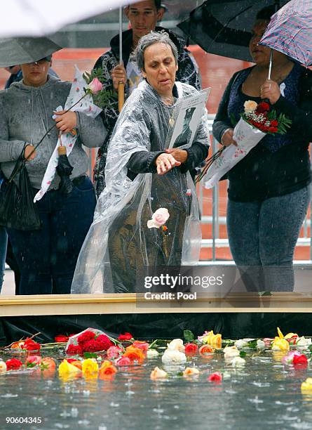 Woman drops a flower into the reflecting pool at Ground Zero during a 9/11 memorial ceremony on September 11, 2009 in New York City. Family of the...