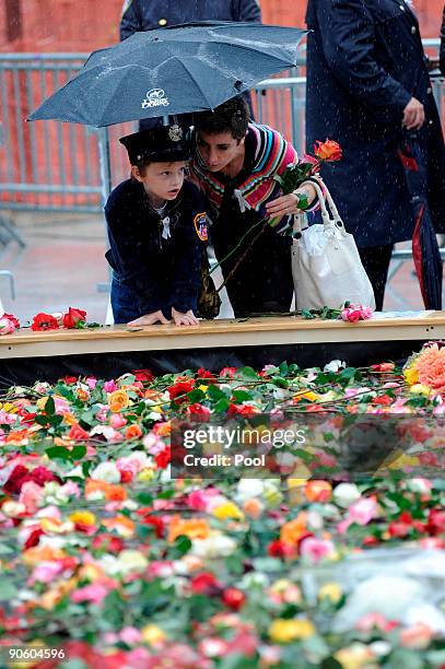 Boy and a woman look over into the flowerd in the reflecting pool at Ground Zero during a 9/11 memorial ceremony on September 11, 2009 in New York...
