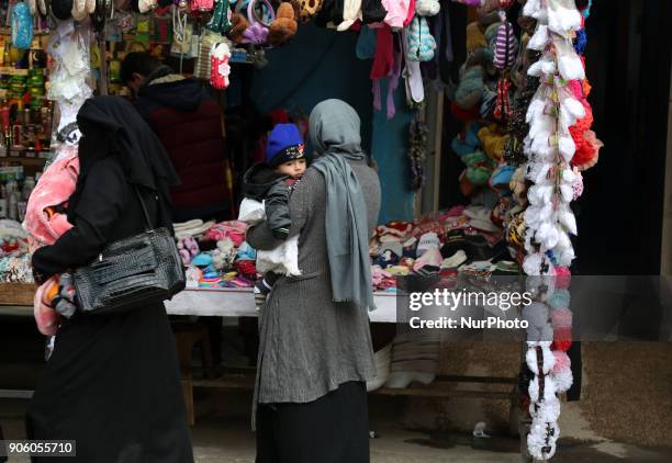 Palestinians walk at a market in al-Nusirat refugee camp in the Gaza strip on January 17, 2018. Gazans are strapped for cash and markets are...