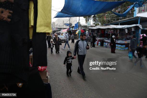 Palestinians walk at a market in al-Nusirat refugee camp in the Gaza strip on January 17, 2018. Gazans are strapped for cash and markets are...