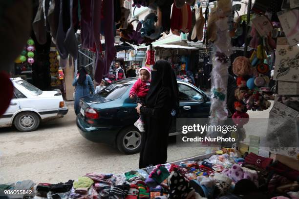 Palestinians walk at a market in al-Nusirat refugee camp in the Gaza strip on January 17, 2018. Gazans are strapped for cash and markets are...