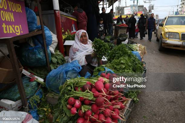 Palestinian woman sells vegetables at a market in al-Nusirat refugee camp in the Gaza strip on January 17, 2018. Gazans are strapped for cash and...