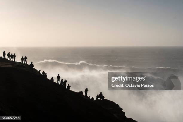 People watch and take photos of the waves and surfers during a surf session at Praia do Norte on January 17, 2018 in Nazare, Portugal.