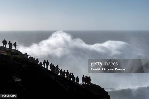 People watch and take photos of the waves and surfers during a surf session at Praia do Norte on January 17, 2018 in Nazare, Portugal.