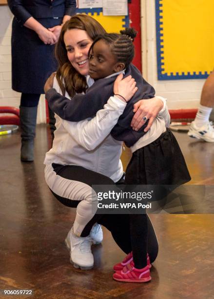 Catherine, Duchess of Cambridge, Patron of the All England Lawn Tennis and Croquet Club receives a hug during a visit to Bond Primary School in...