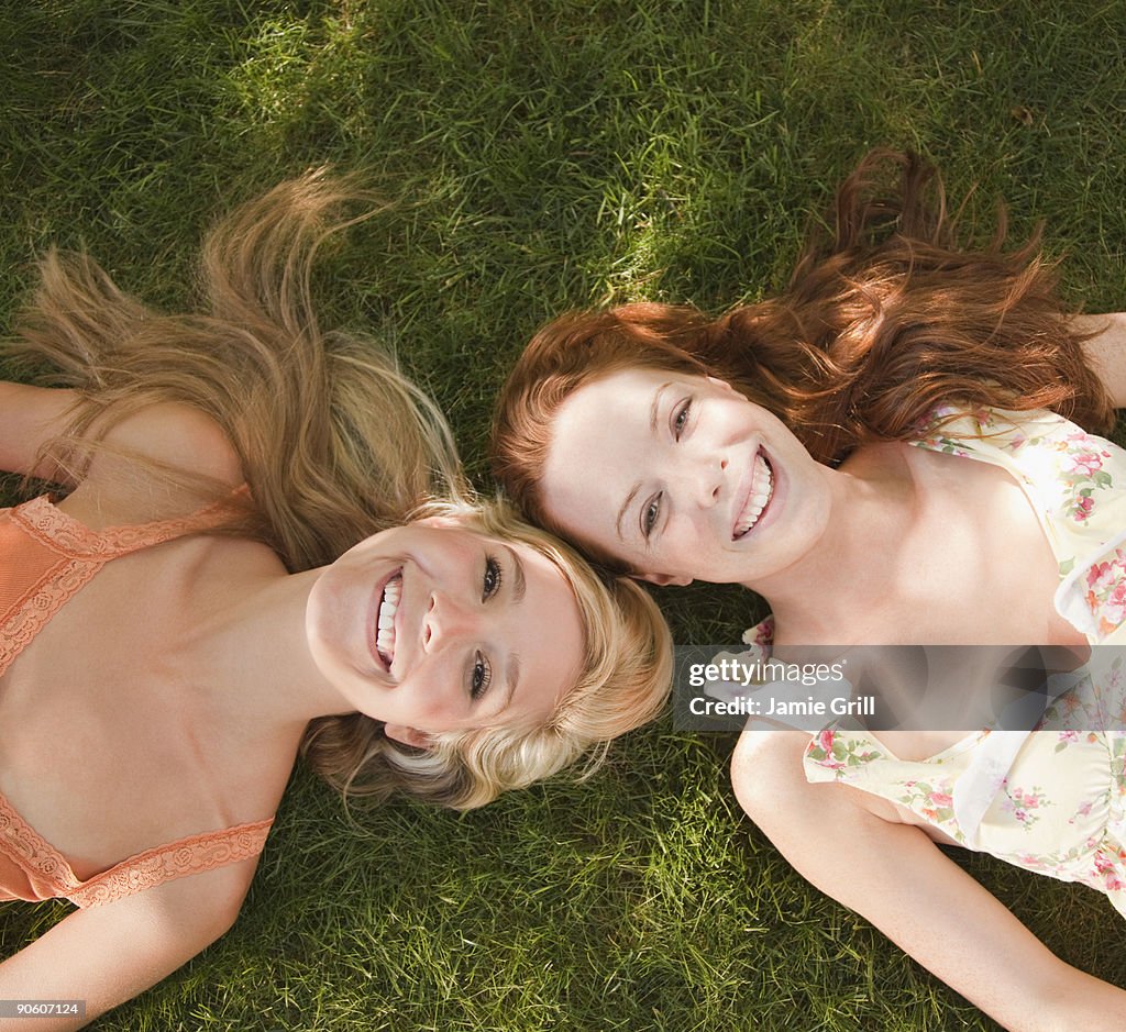 Two women lying grass together