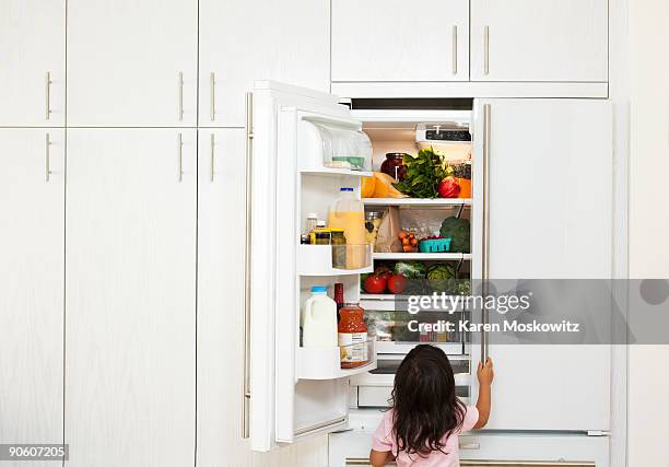 girl looking in refrigerator - full fridge stockfoto's en -beelden