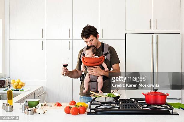 man holding baby while cooking - rolwisseling stockfoto's en -beelden