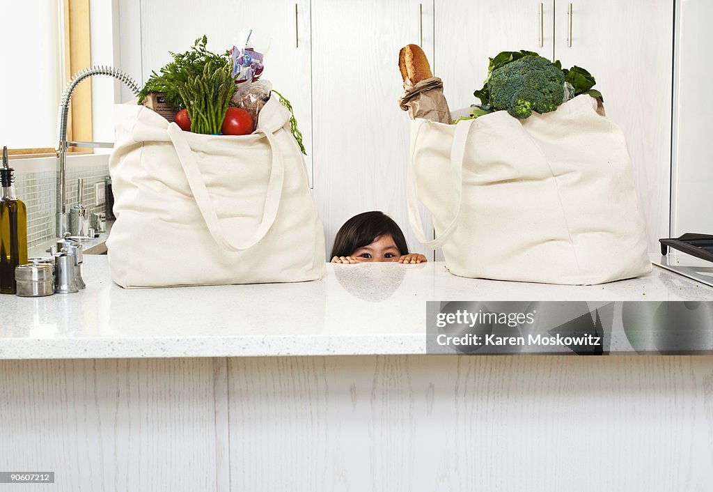 Girl peering over counter with groceries