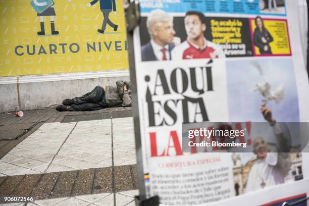 Man sleeps on the street as a newspaper displays the image of Pope Francis ahead of a visit in Santiago, Chile, on Monday, Jan. 15, 2018. 400,000...