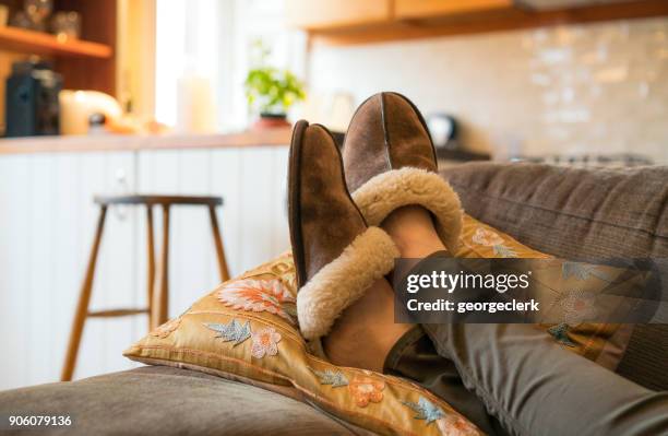 relajación merecido: pies para arriba en el sofá - zapatilla fotografías e imágenes de stock