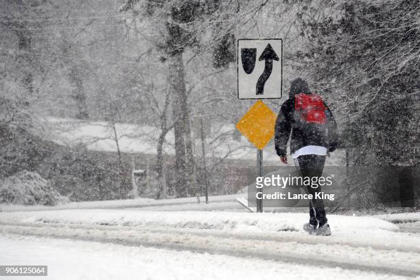 Man walks along Ridge Road as snow falls on January 17, 2018 in Raleigh, North Carolina. Governor Roy Cooper declared a State of Emergency yesterday...