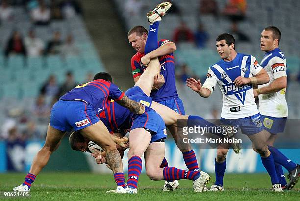Josh Morris is tackled by Matt Hilder and Chris Houston of the Knights during the third NRL qualifying final match between the Bulldogs and the...
