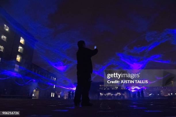 Man takes a photograph of Waterlicht by Dutch artist Daan Roosegaarde, part of the Lumiere London light festival in London on January 17, 2018....