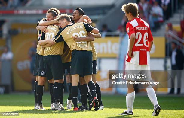 Niko Bungert of Mainz looks dejected and the team of Hertha celebrates scoring the first goal during the Bundesliga match between FSV Mainz 05 and...