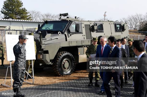 Visiting Australian Prime Minister Malcolm Turnbull and Japanese Prime Minister Shinzo Abe walk towards an Australian-made Bushmaster protected...