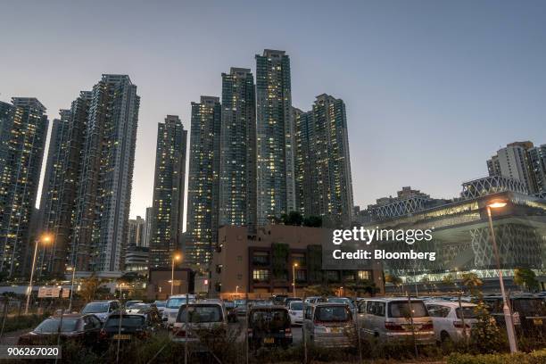 Vehicles sit at a car park in front of illuminated residential buildings at the Metro Town development, jointly developed by CK Asset Property...