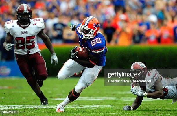 Omarius Hines of the Florida Gators runs past Bryan Willis and Xavier Lamb of the Troy Trojans during game at Ben Hill Griffin Stadium on September...