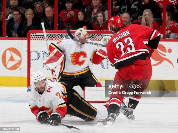 Brock McGinn of the Carolina Hurricanes shoots a puck that rings off both pipes as Mike Smith of the Calgary Flames attempts to make a save and...