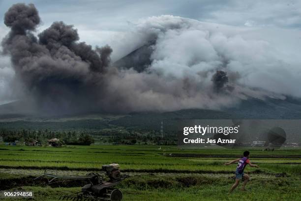 Boy runs as pyroclastic clouds emit from Mayon volcano on January 17, 2018 in Camalig, Philippines. Thousands evacuate as Philippines' Mayon volcano...