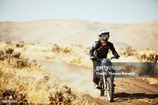 woman riding dirt bike on desert road on summer afternoon - motocross stock photos et images de collection