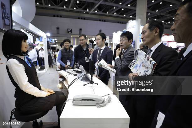 Attendees watch as a Kokoro Co. Actroid humanoid robot using Kyoei Sangyo Co.'s "RecepROID" software performs during a demonstration at the RoboDEX...