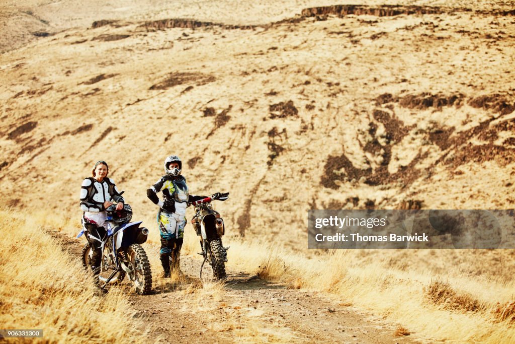 Female dirt bike riders resting during ride on desert road