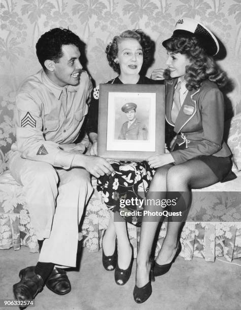 View of, from left, Sergeant Eduardo Cansino Jr , his mother, actress Volga Hayworth , and sister, actress Rita Hayworth , as they sit together on a...