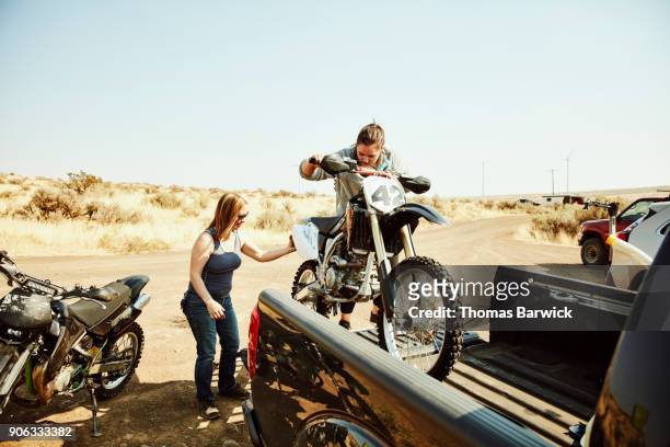 women taking dirt bike out of bed of truck before desert ride - pick up truck stock pictures, royalty-free photos & images