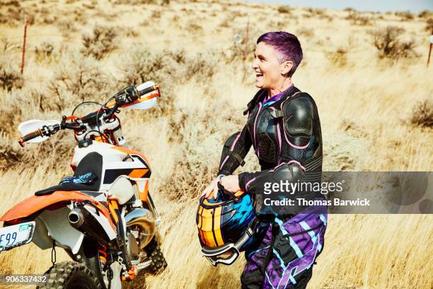 laughing woman preparing to put on helmet before dirt bike ride in desert with friends - older woman colored hair stock pictures, royalty-free photos & images