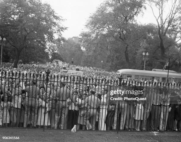 View, from inside the fence, as MPs hold back crowds gathered near the White House following the Nagasaki atomic blast and the subsequent...
