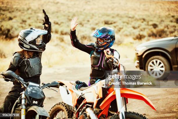 two women high fiving after dirt bike ride in desert - 電單車比賽 個照片及圖片檔