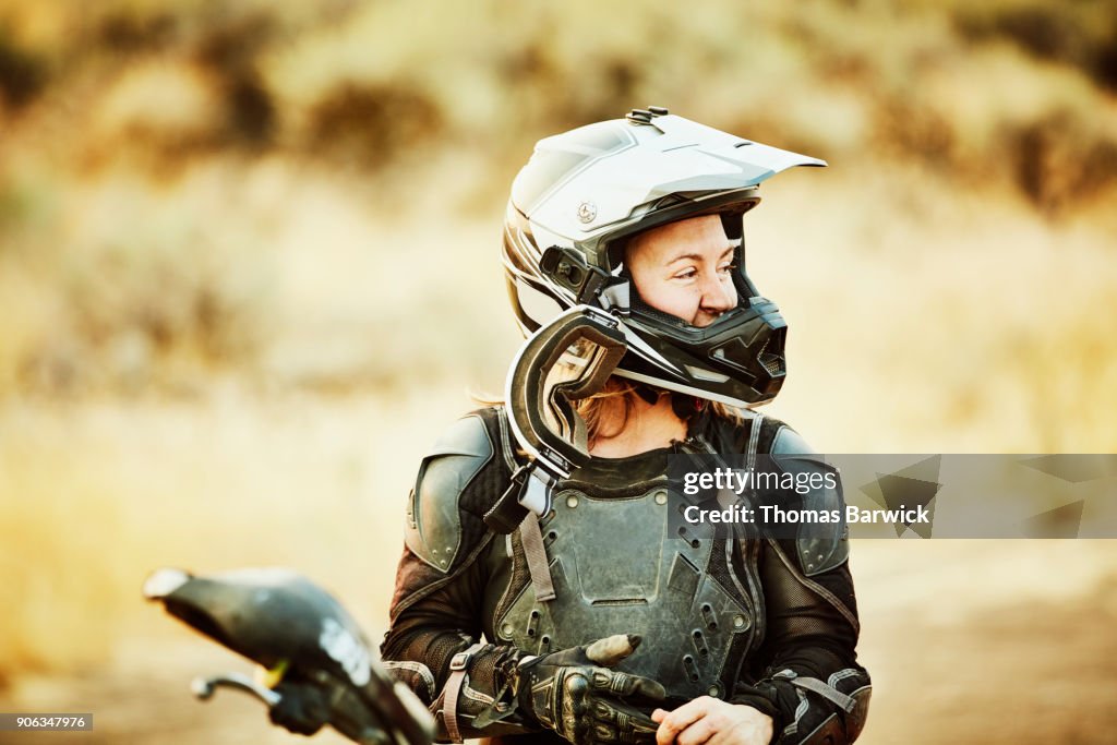 Woman with dirt on face smiling after riding dirt bikes in desert with friends