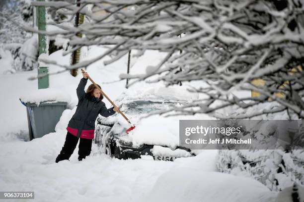 Villager clears snow from a car, following extensive snowfall during the last forty eight hours on January 18, 2018 in Leadhills, Scotland. Motorists...