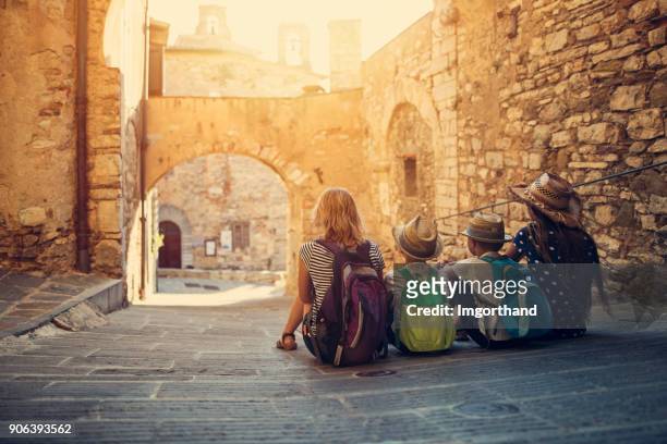 famiglia di turisti che si gode la tranquilla strada della piccola città italiana - turista foto e immagini stock