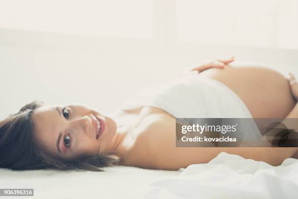 beautiful pregnant woman lying on the bed - baby girl laying on tummy stock pictures, royalty-free photos & images