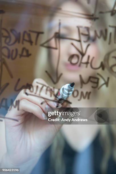 young businesswoman writing with a marker on glass - andy andrews stock-fotos und bilder