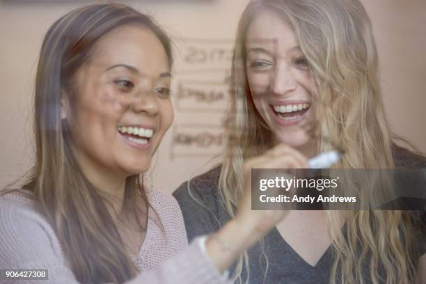 young businesswomen writing with a marker on glass - andy andrews stockfoto's en -beelden