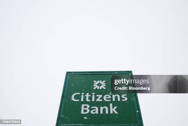 Snow falls in front of signage outside a Citizens Financial Group Inc. Bank branch in downtown Portsmouth, Ohio, U.S., on Tuesday, Jan. 18, 2018....