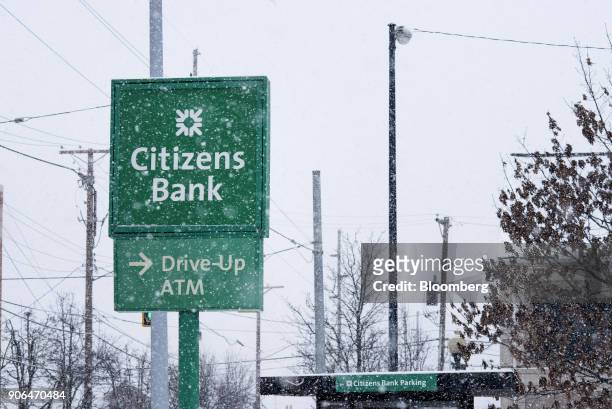 Snow falls in front of signage outside a Citizens Financial Group Inc. Bank branch in downtown Portsmouth, Ohio, U.S., on Tuesday, Jan. 18, 2018....