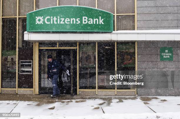 United States Postal Service letter carrier exits from a Citizens Financial Group Inc. Bank branch as snow falls in downtown Portsmouth, Ohio, U.S.,...