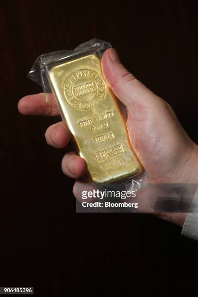An employee holds a one kilogram bar of gold at the Sharps Pixley Ltd. Showroom in this arranged photograph in London, U.K., on Thursday, Jan. 18,...